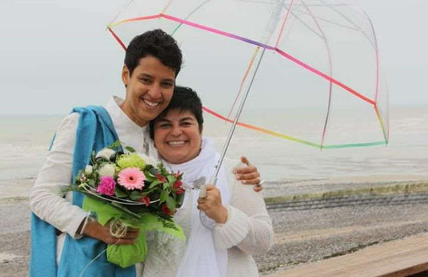Mariama Diallo (L) and Christina Palma (R) under a rainbow umbrella holding flowers